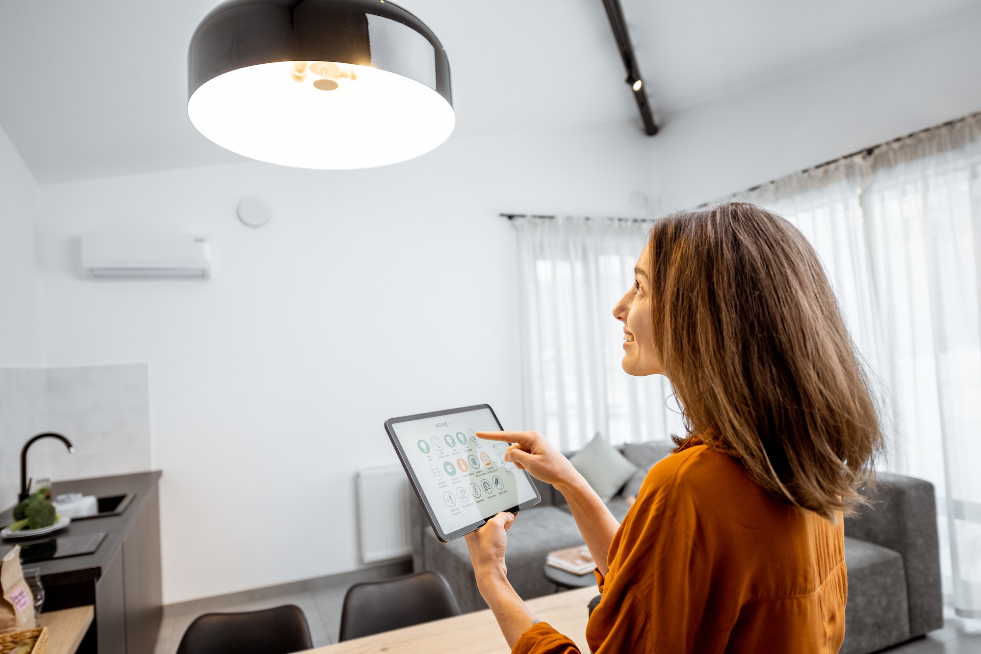 Mujer controlando la luz con una tableta digital en casa