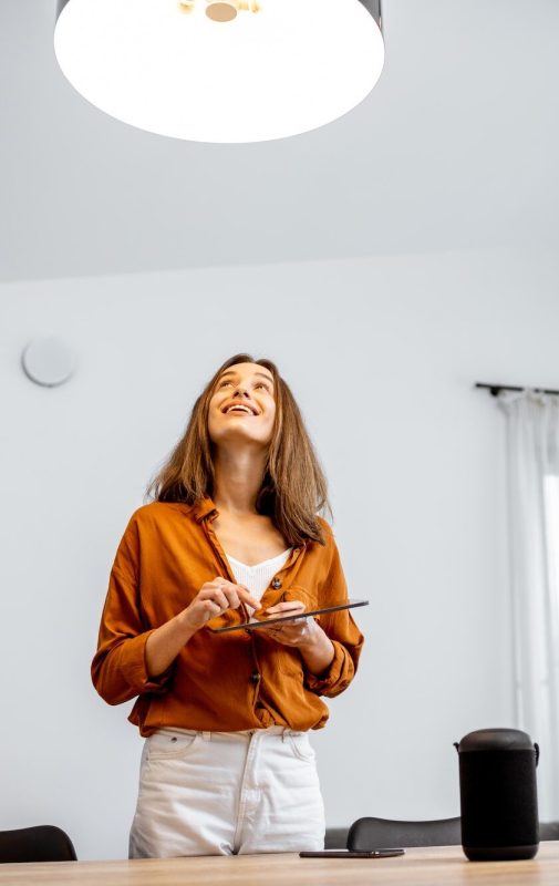Mujer controlando la luz con un hogar inteligente en casa